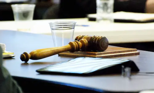 Wooden court gavel on a courtroom table alongside a glass of water