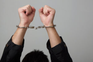 Photo of wrists raised up with handcuffs on them