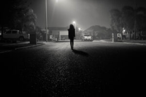 Dark silhouette of a person walking down a lit street